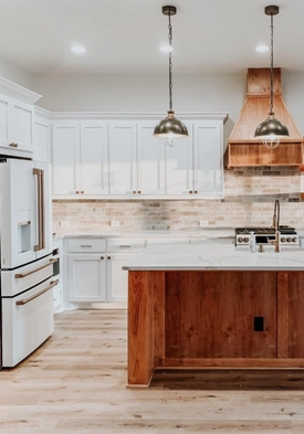 wood look oak flooring in kitchen with white cabinets and dark wood island, and stone look subway tile backsplash